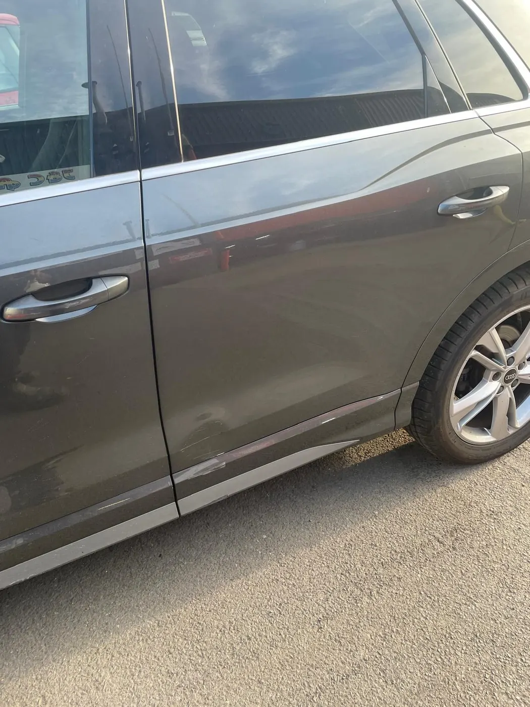 Before: Grey Audi with a creased dent along the rear door