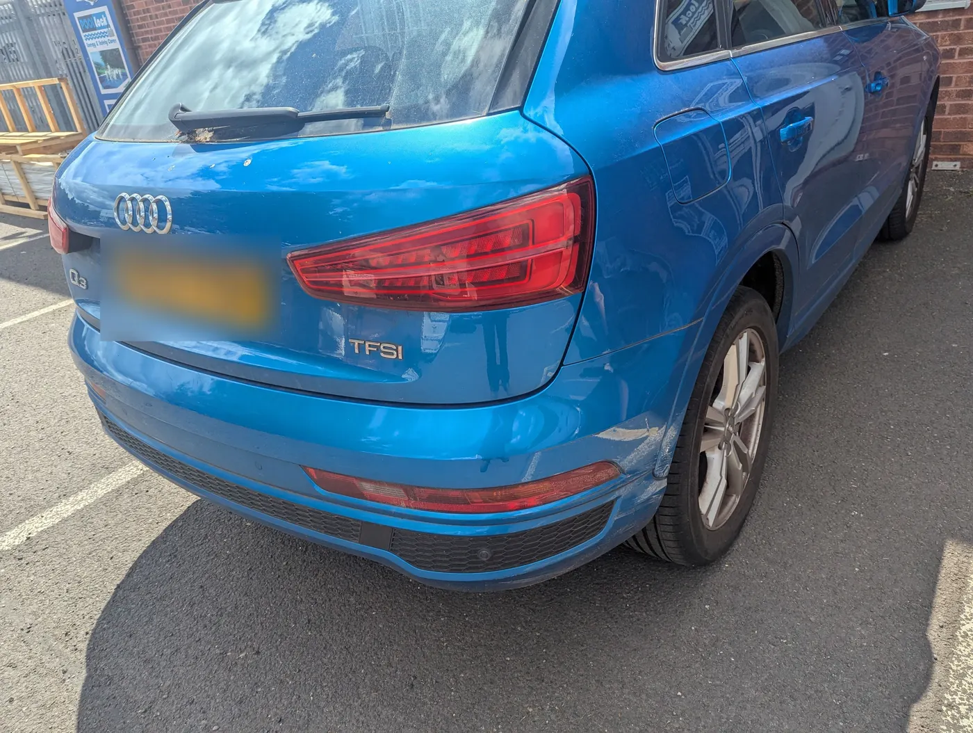 Before: Blue Audi Q3 with accident damage crushing the rear corner panel next to the tail light