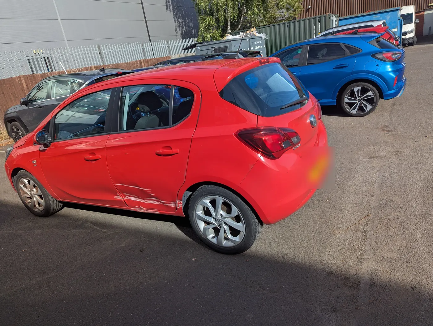 Before: Red Vauxhall Corsa with a dent and scrape along the rear door and sill